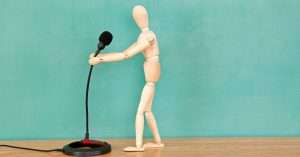 a wooden doll holding a microphone